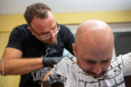 Tattoo artist works on a boy's back.