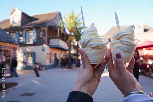 Hand holds up a cup of soft serve pineapple vanilla swirl ice cream, in the historic district of St. Augustine Florida photo