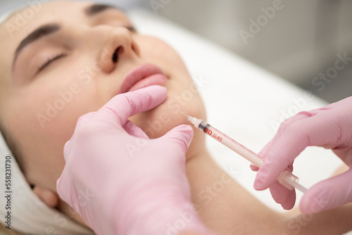 Close-up of the hands of an expert cosmetologist injecting botox into a woman's chin  Correction filler . beauty injection concept.