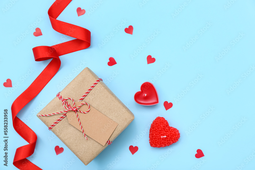 Gift with candles, hearts and red ribbon on blue background. Valentine's Day celebration