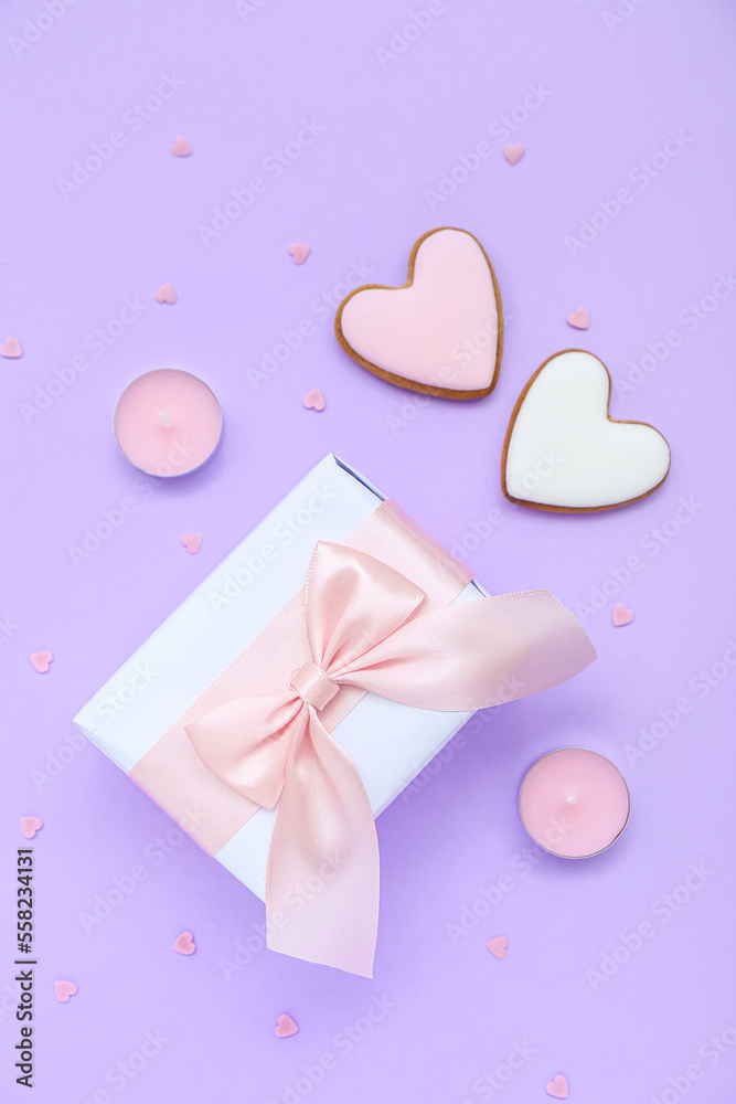 Gift with cookies, candles and hearts on lilac background. Valentine's Day celebration