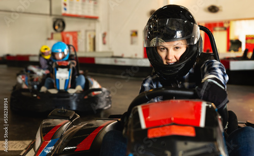 Portrait of female racer in helmet driving the kart on track © JackF
