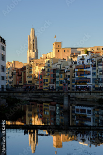 Famous gothic Cathedral landmark over the skyline in Girona reflected with the quiet river houses on a bright sunset blue sky © jordieasy