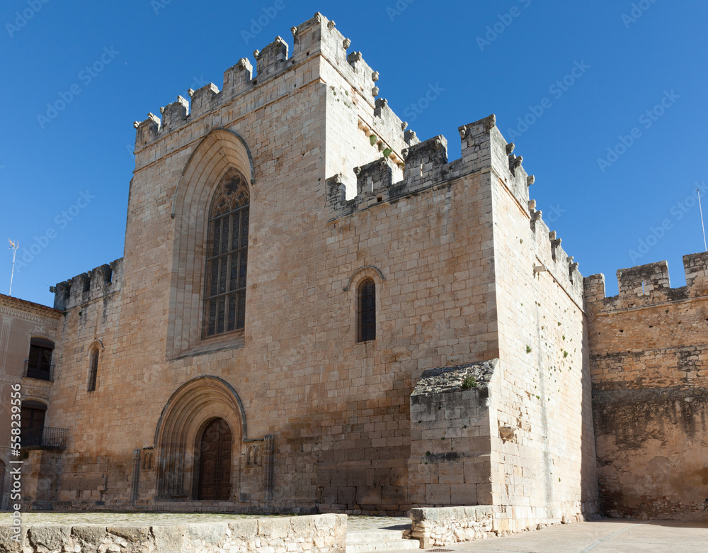 View of church main facade with Gothic stained glass window in courtyard of medieval Santes Creus Monastery, Aiguamurcia, Spain..