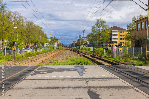 Beautiful view of railway crossing over railway and car parking in city center, enclosed by fence. Sweden.