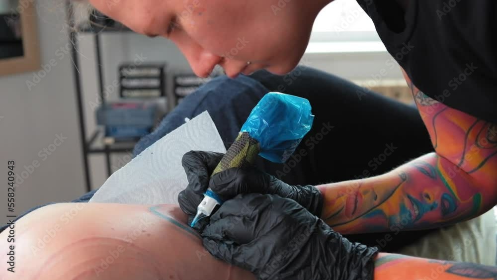 Tattoo artist girl at work.A feminist with dreadlocks gets a tattoo.A strong woman gets a tattoo