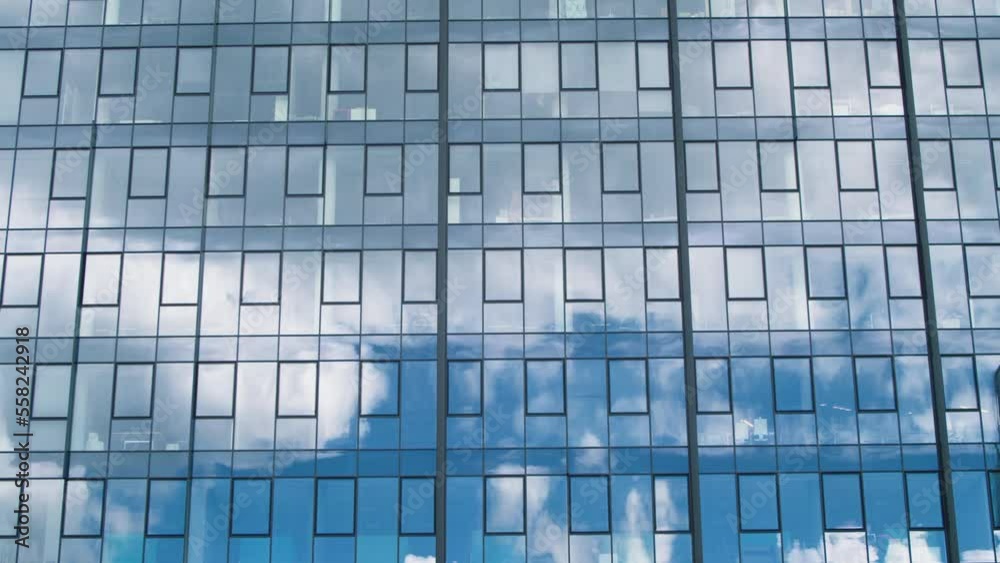 Time lapse of a glass skyscraper with clouds reflected in the office windows. Clouds reflected in glass windows of offices. Time lapse of blue sky and clouds reflected in structural modular glass wall Time lapse of a glass skyscraper with clouds reflected in the office windows. Clouds reflected in glass windows of offices. Time lapse of blue sky and clouds reflected in structural modular glass wall