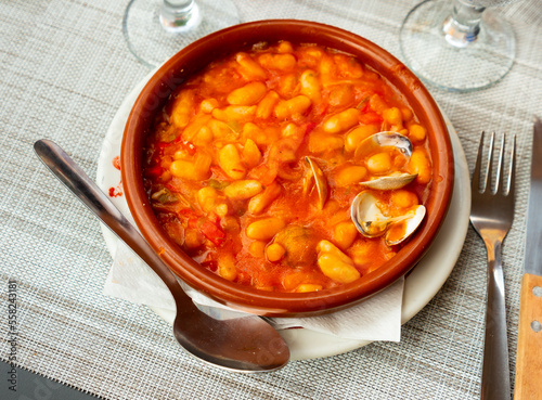 Tasty white bean stew with clams in bowl, popular spanish dish