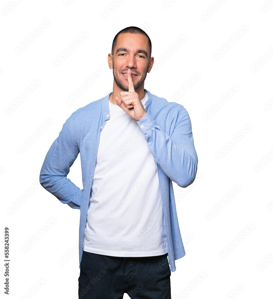 Happy young man asking for silence gesturing with his finger Happy young man asking for silence gesturing with his finger