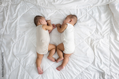 Foto Happy childhood, Sleeping newborn identical boy twins on the bed on bedroom, Asi