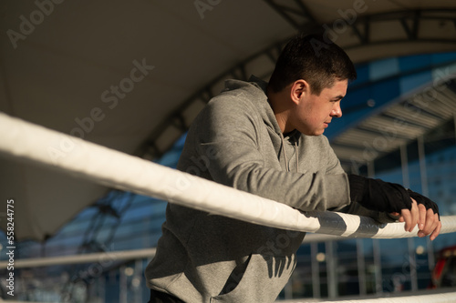 Caucasian male boxer resting in the ring outdoors. 