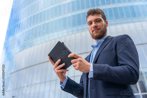 Male businessman or entrepreneur outside the office, business park with a glass building