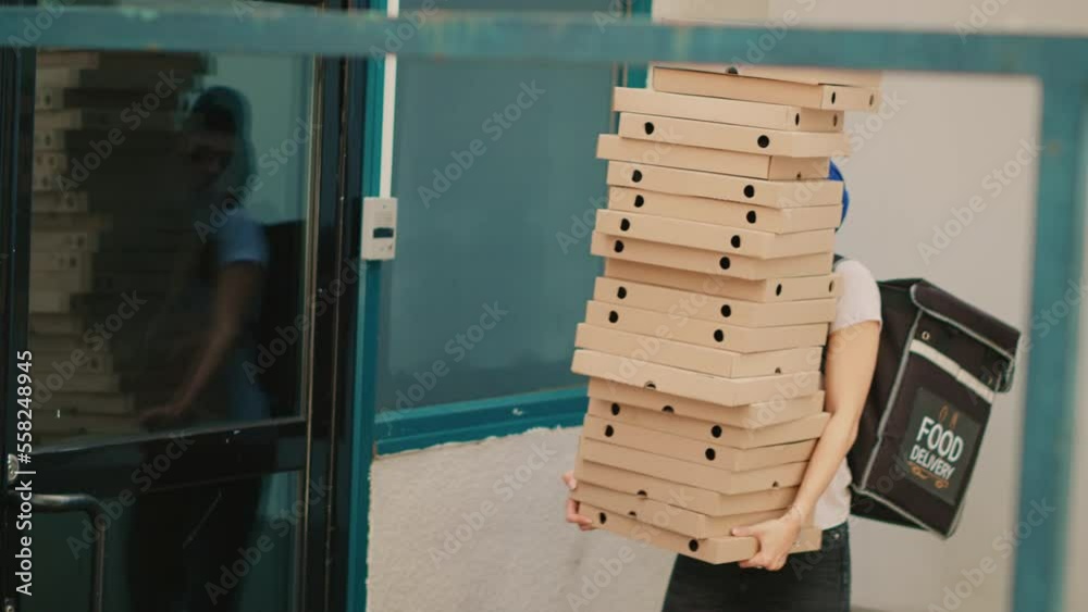 Fastfood meal courier dropping pizza boxes pile outside building, clumsy takeaway worker stumbling and running scared. Bad delivery service, pizzeria employee with falling packages. Handheld shot.