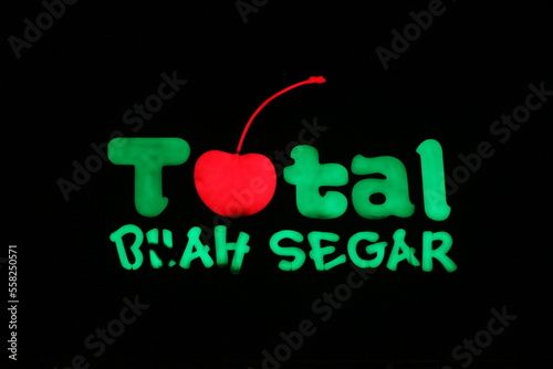 Bekasi, Indonesia in July 2022. The TOTAL Buah Segar logo shining brightly at night against the dark night sky. photo