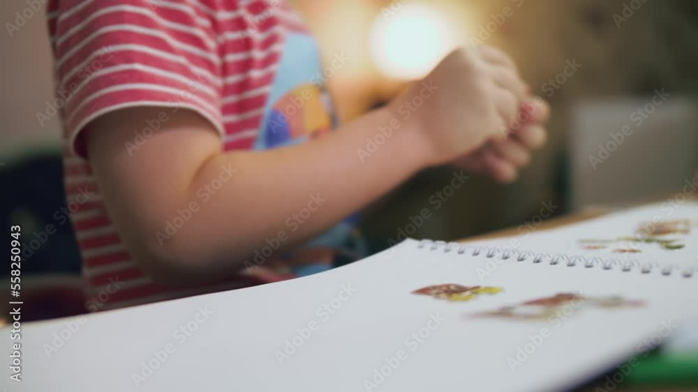 On the eve of the New Year а boy of preschool age in macro photography with children's hands carefully glues stickers into the album, which is a creative and children's game. On the eve of the New Year а boy of preschool age in macro photography with children's hands carefully glues stickers into the album, which is a creative and children's game.
