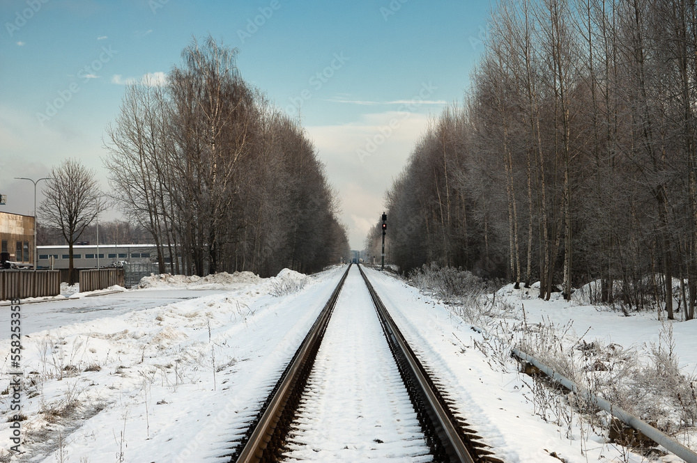 railway in winter, forest and blue sky in the background