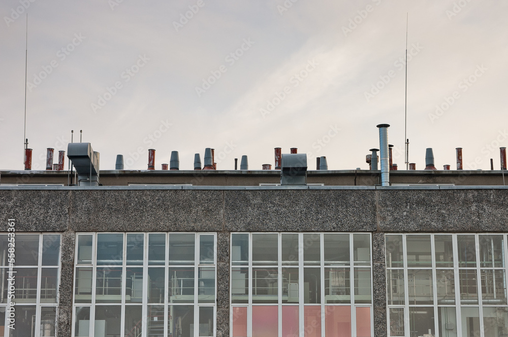 the roof of a building with a large number of ventilation pipes on a gray sky background the roof of a building with a large number of ventilation pipes on a gray sky background