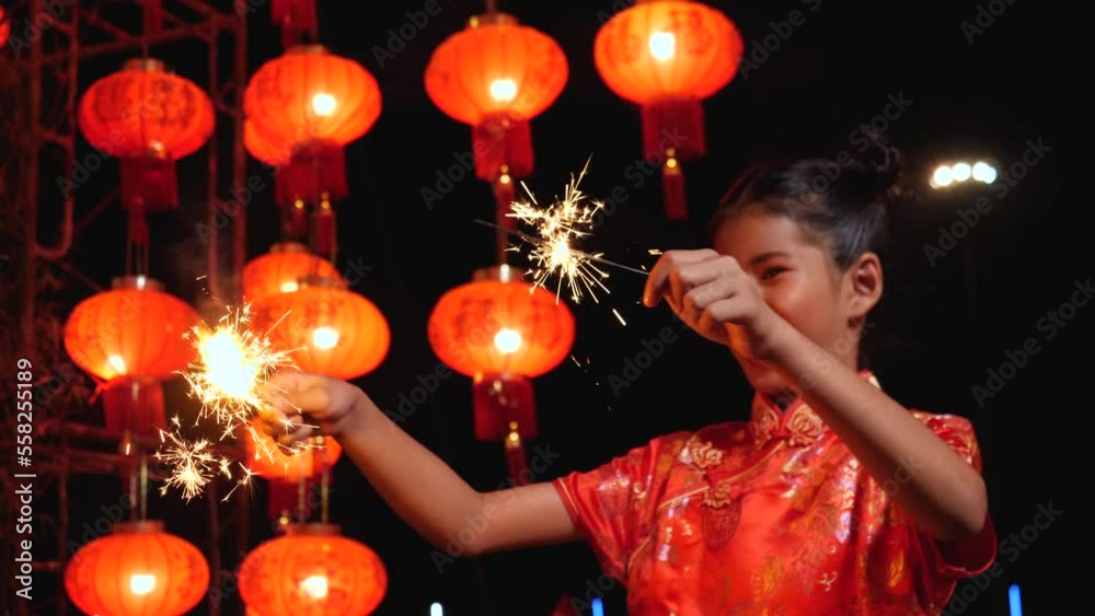 Happy little girl in Chinese dress playing fireworks Chinese new year at night