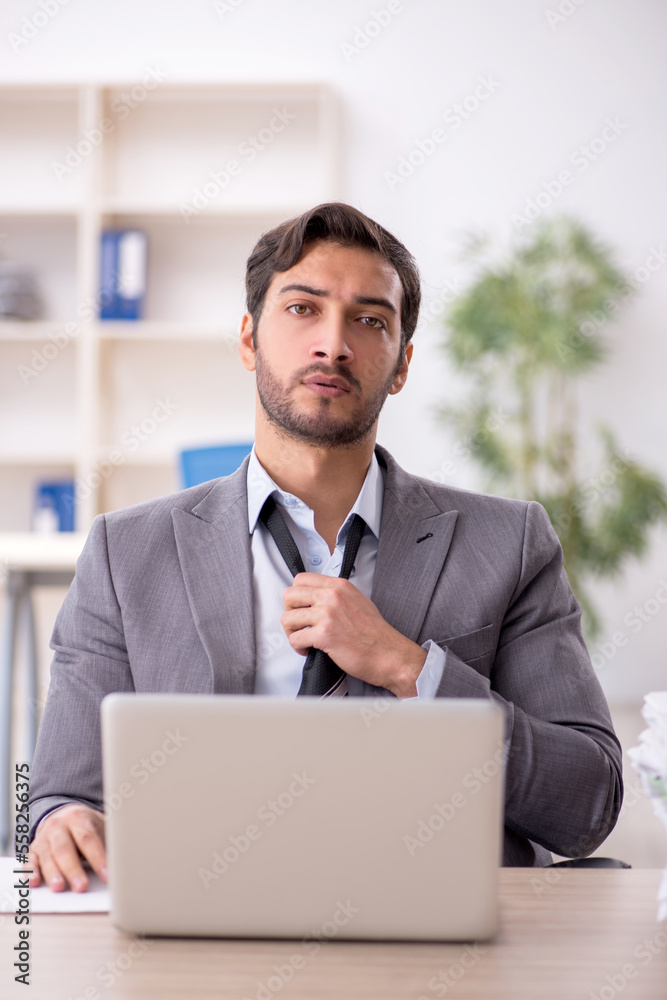 Young male employee and too much work in the office Young male employee and too much work in the office