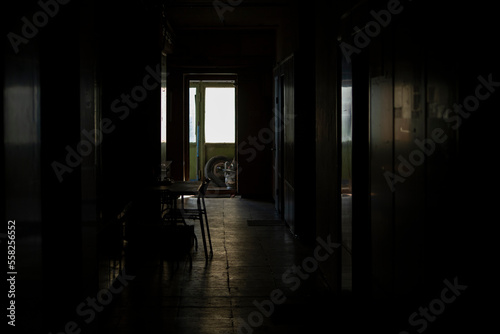 Interior light from window. Dark corridor and light at end. Reflection on floor.