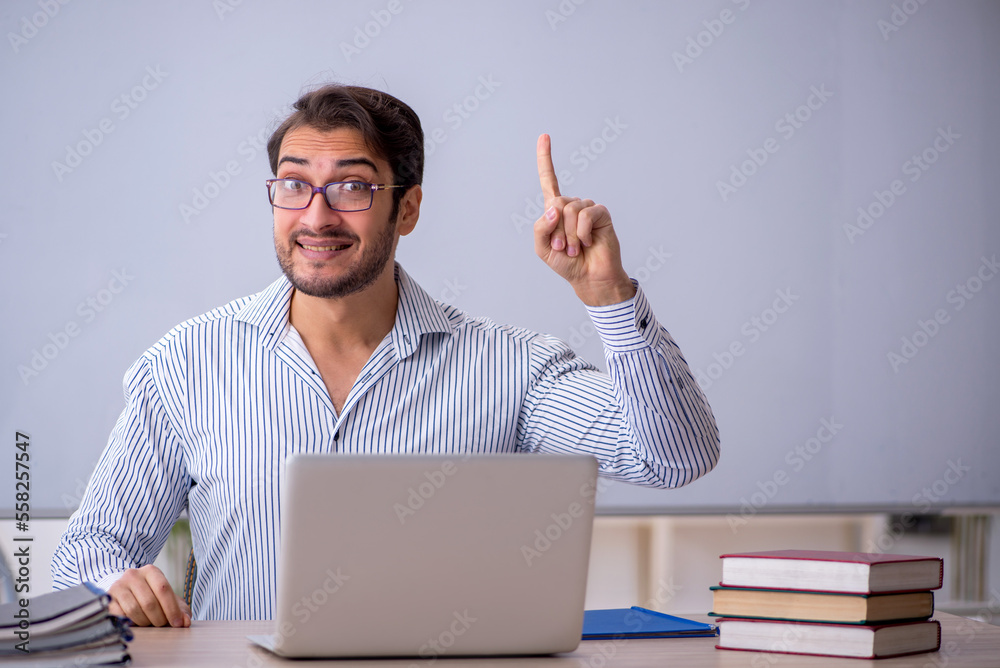 Young male teacher sitting in the classroom Young male teacher sitting in the classroom