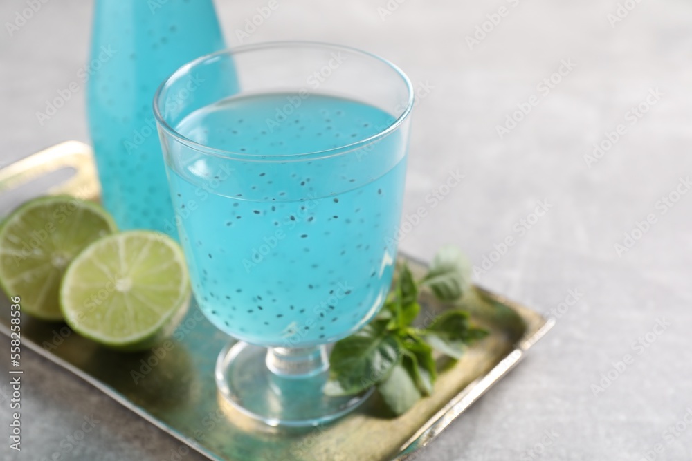 Tasty light blue drink with basil seeds on grey table