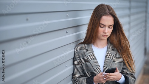 Canvas Print A disgruntled girl stares into a smartphone against a striped wall
