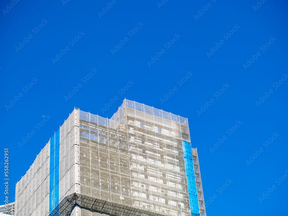 Building under construction wrapped blue and white protection safety net. Building under construction wrapped blue and white protection safety net.