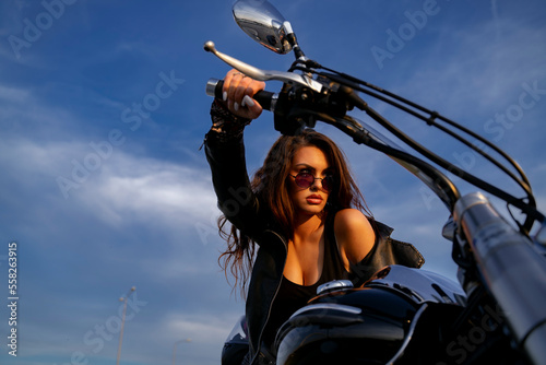 Closeup, sexy girl sitting on motorcycle and watching sunset, holding handle bar 