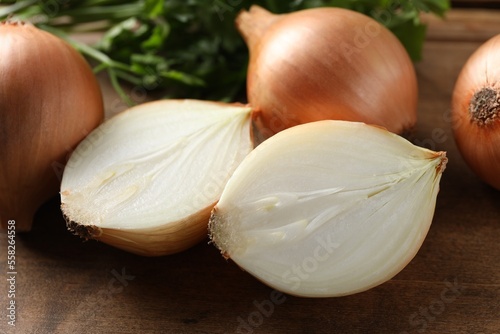 Whole and cut onions on wooden board  closeup