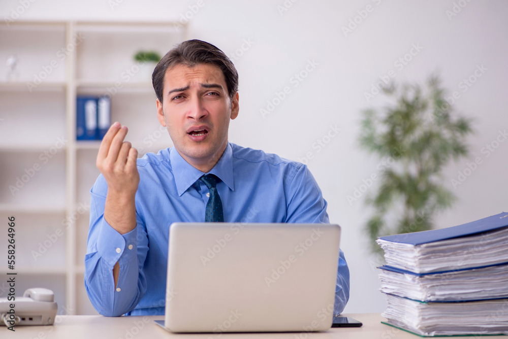 Young male employee and too much work in the office Young male employee and too much work in the office