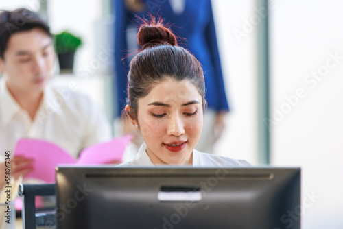 Millennial Asian professional successful female businesswoman mentor in formal suit standing pointing helping male businessman trainee learning writing short note memo in company office workstation