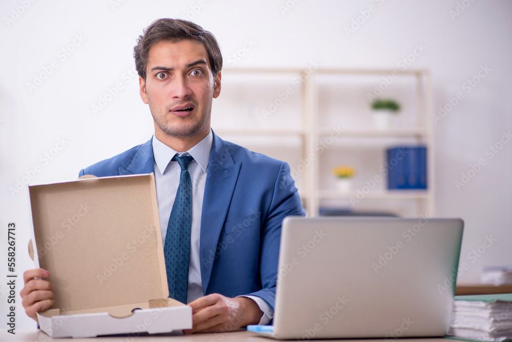 Young male employee eating pizza at workplace
