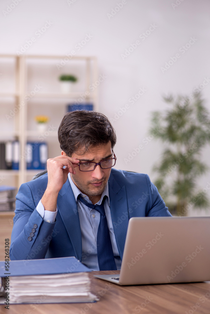 Young male employee and too much work in the office Young male employee and too much work in the office