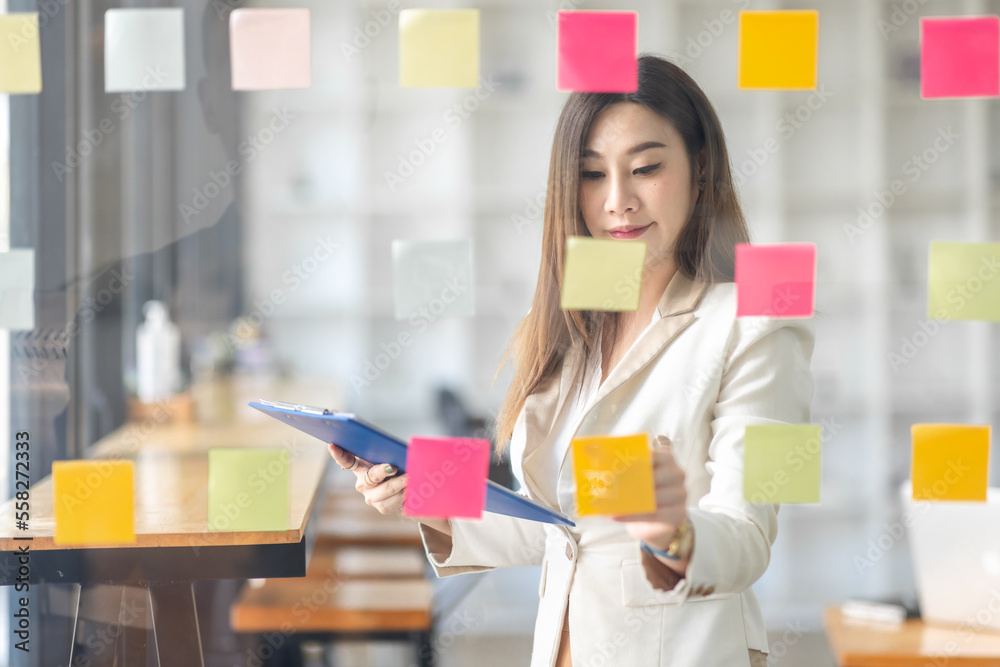 Business female employee with many conflicting priorities arranging sticky notes commenting and brainstorming on work priorities colleague in a modern office.
Business female employee with many conflicting priorities arranging sticky notes commenting and brainstorming on work priorities colleague in a modern office.