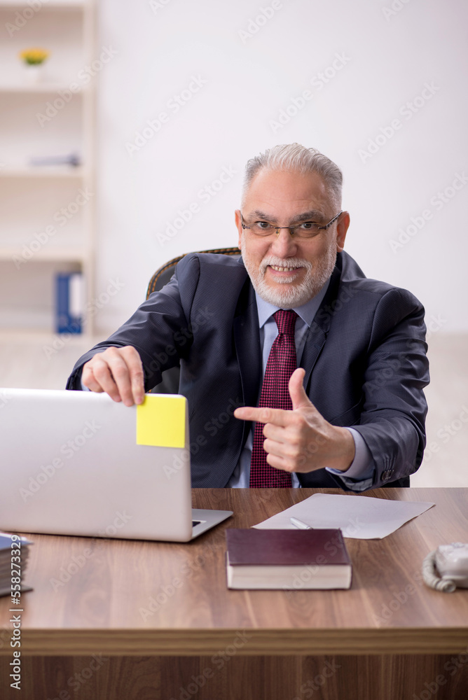 Old male boss working at workplace Old male boss working at workplace