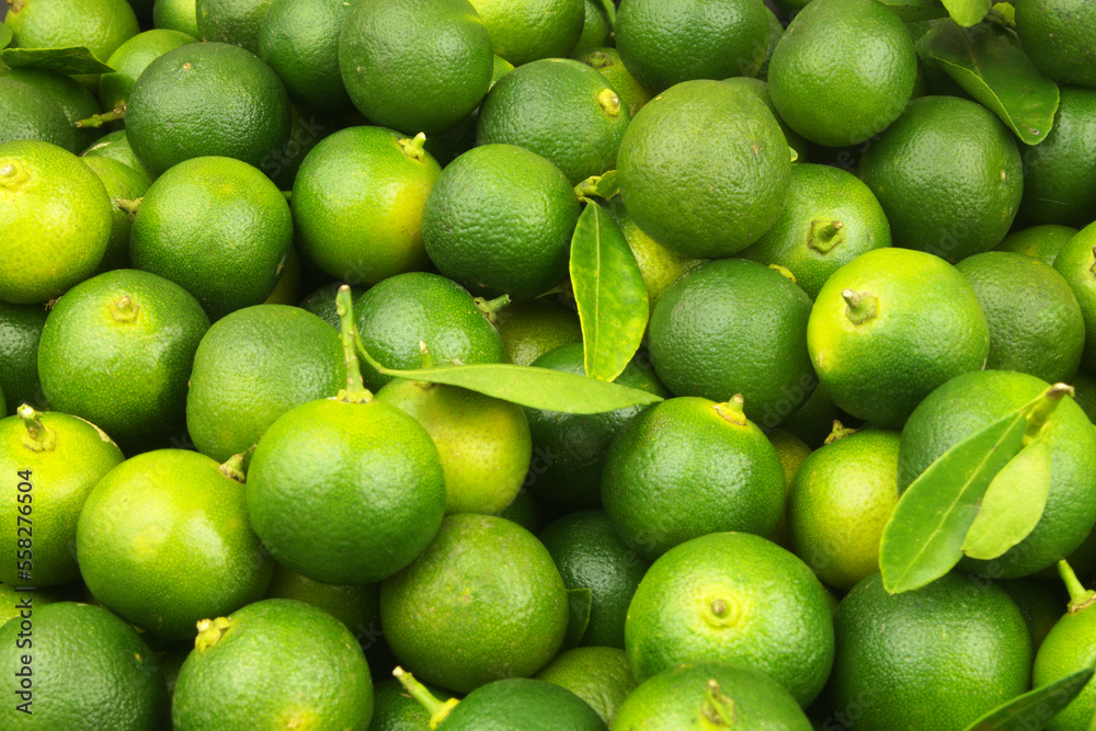 Fresh green limes with leaves as background