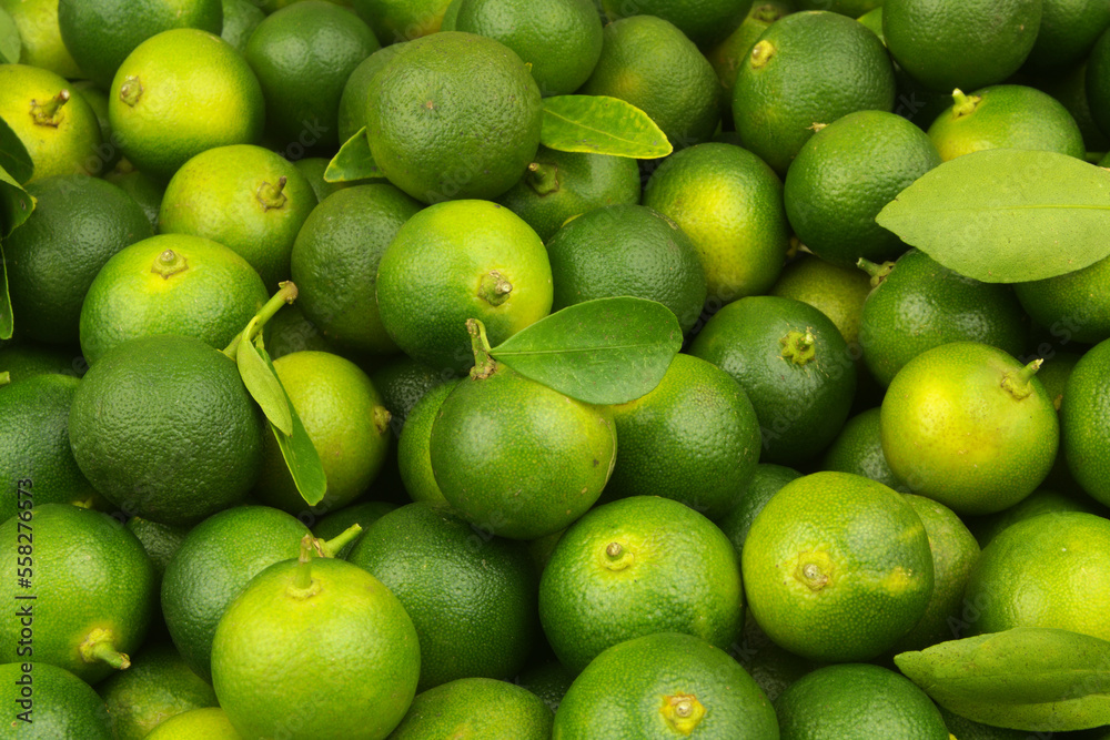 Green limes with fresh leaves as background or texture