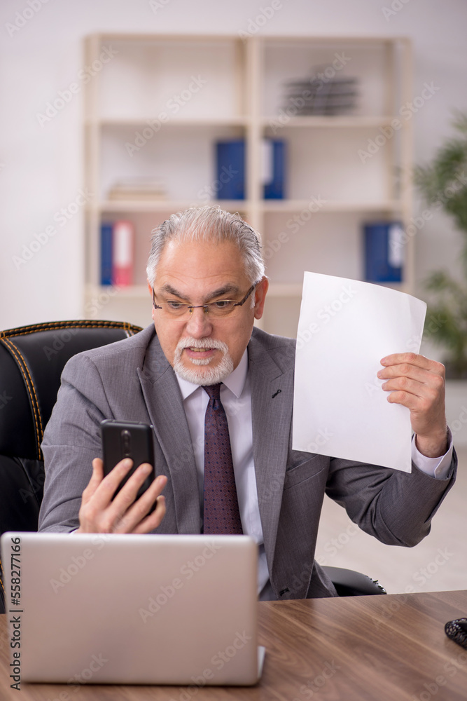 Old male employee working in the office Old male employee working in the office