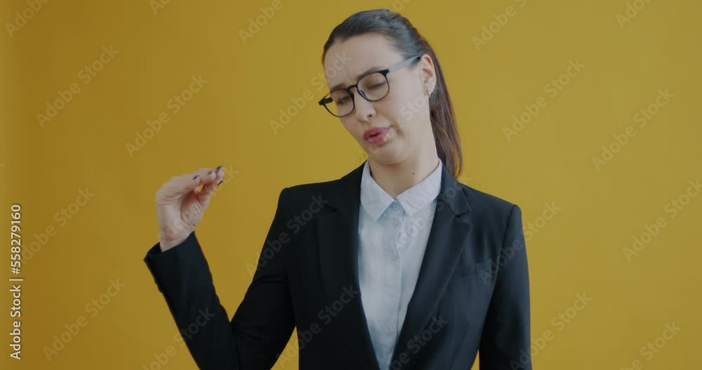 Portrait of young business lady making Bla bla bla hand gesture complaining of too much talk on yellow background. People and communication concept.