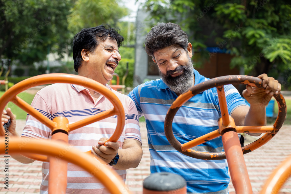 Obraz premium Indian mature senior men exercises on the public park gym equipment outdoor.