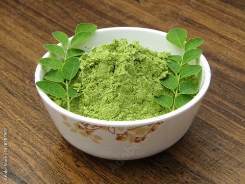 Moringa oleifera leaves powder in a bowl on wooden background