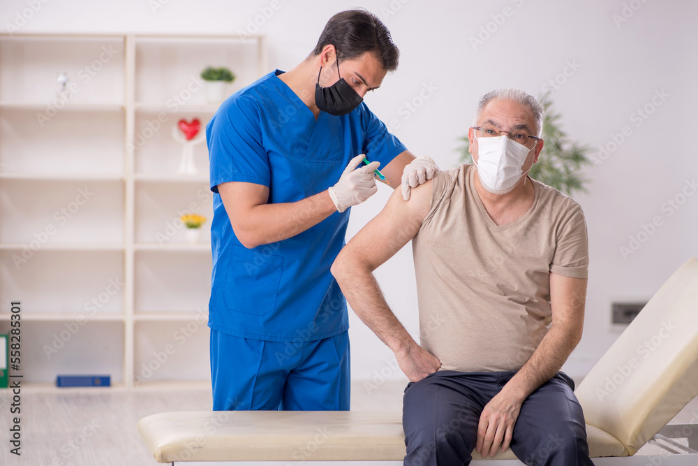 Obraz premium Old male patient visiting young male doctor in vaccination conce