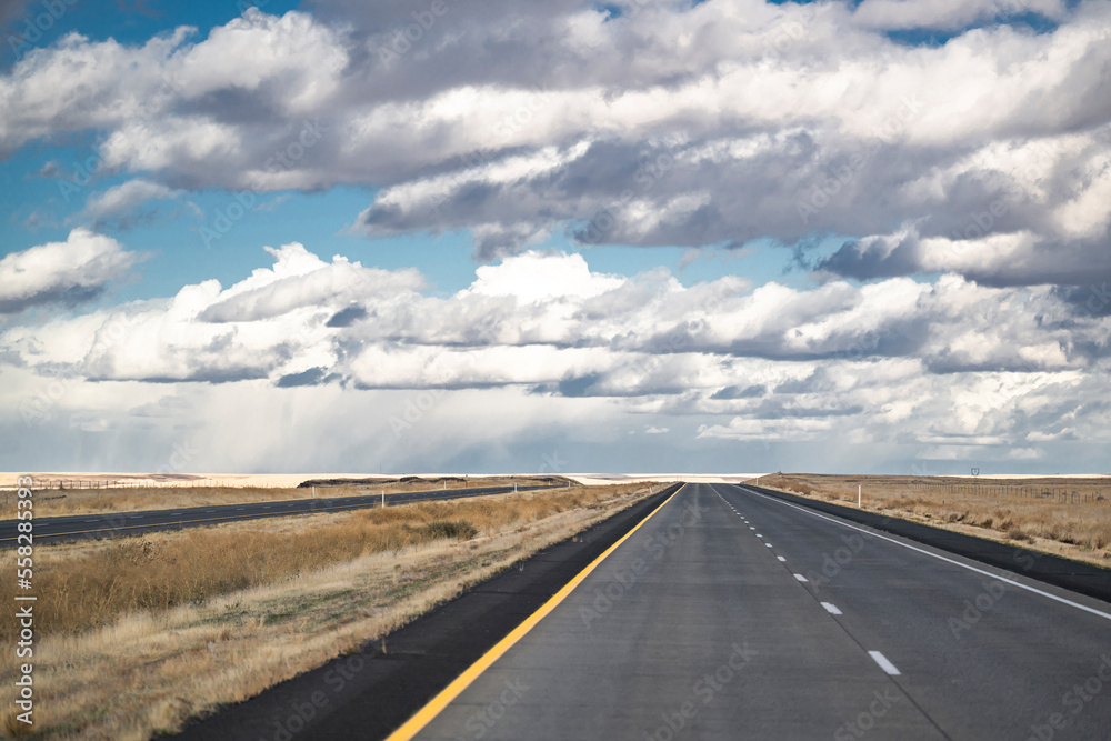 Wide road resting on the horizon with fields with neatly cut grass beckons forward tourists and travelers exploring new places and routes