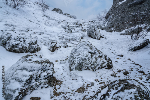 Trail between rocks with snow and ice to Mount Alenga near Southern Demerdzhi in snow and ice in spring. Crimea