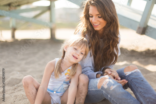 Mother and daughter smiling together on a sunny beach in califor photo