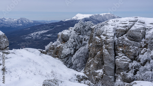 Rocks on Southern Demerdzhi mountain in snow after blizzard in spring. And view of Chatyr-Dag. Crimea