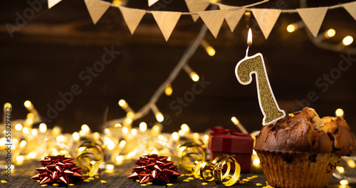 Number 7 gold burning candle in a cupcake against celebration wooden background with lights. Birthday cupcake. Copy space. photo