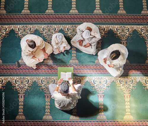 Above mosque carpet, group and quran for faith, religion and prayer for gratitude, peace or mindfulness. Imam, praying and spiritual development with book, focus and islamic worship on floor in Qatar photo