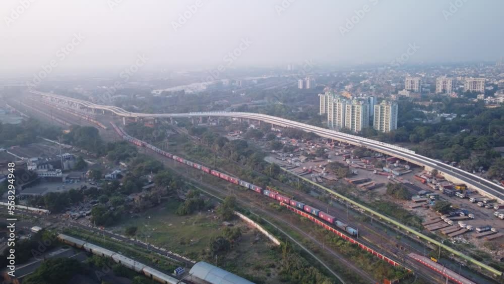 Aerial view of rail freight transport slowly entering the railway station alongside flyover with Loha Mart Garage and city view at background, West Bengal, Kolkata, India Aerial view of rail freight transport slowly entering the railway station alongside flyover with Loha Mart Garage and city view at background, West Bengal, Kolkata, India